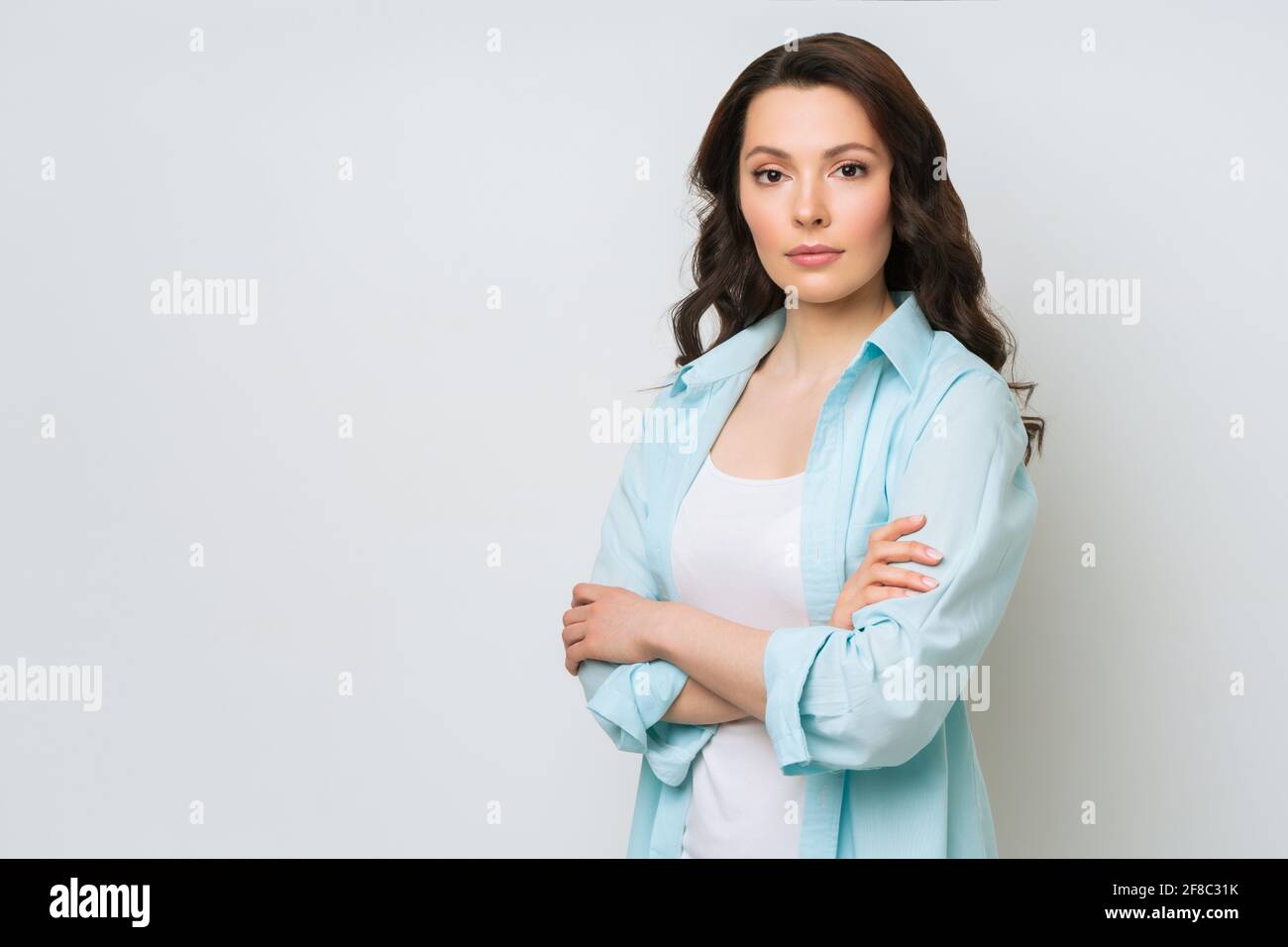 Young woman portrait. Adorable brunette in a sweater looking at the camera with her arms crossed. Stock Photo