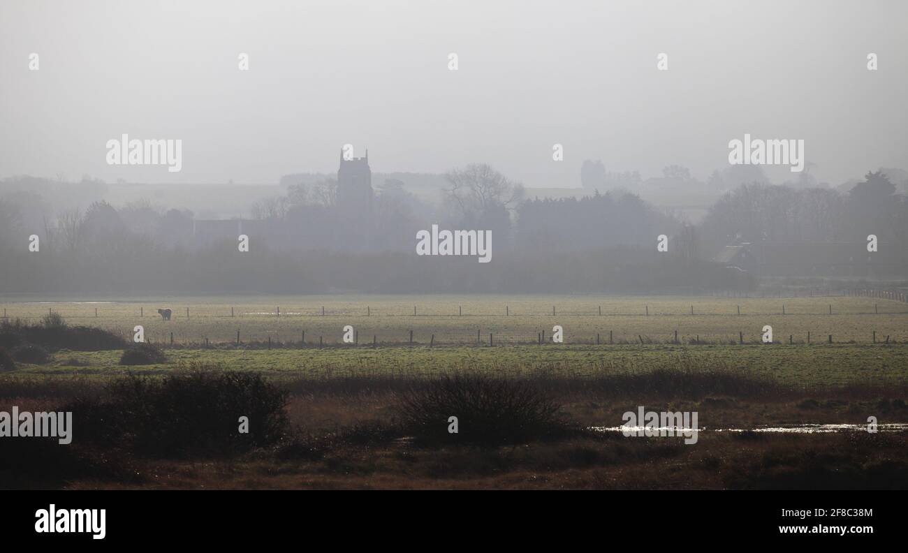 Holme-next-the-Sea church on a misty winter morning seen across the grazing marshes. Stock Photo
