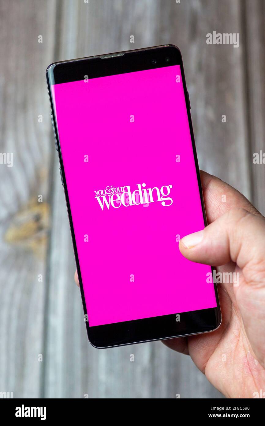 A Mobile phone or cell phone being held in a hand with the You and your wedding app open on screen Stock Photo
