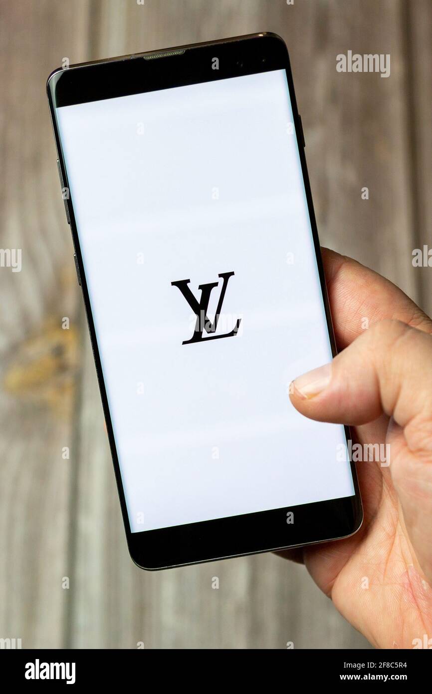 A Mobile phone or cell phone being held in a hand with the Louis Vuitton  app open on screen Stock Photo - Alamy