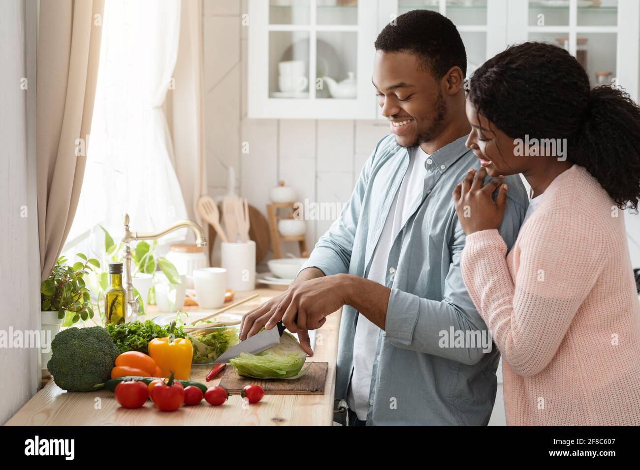 Cooking Together. Portrait of happy affectionate black couple preparing lunch in kitchen Stock Photo