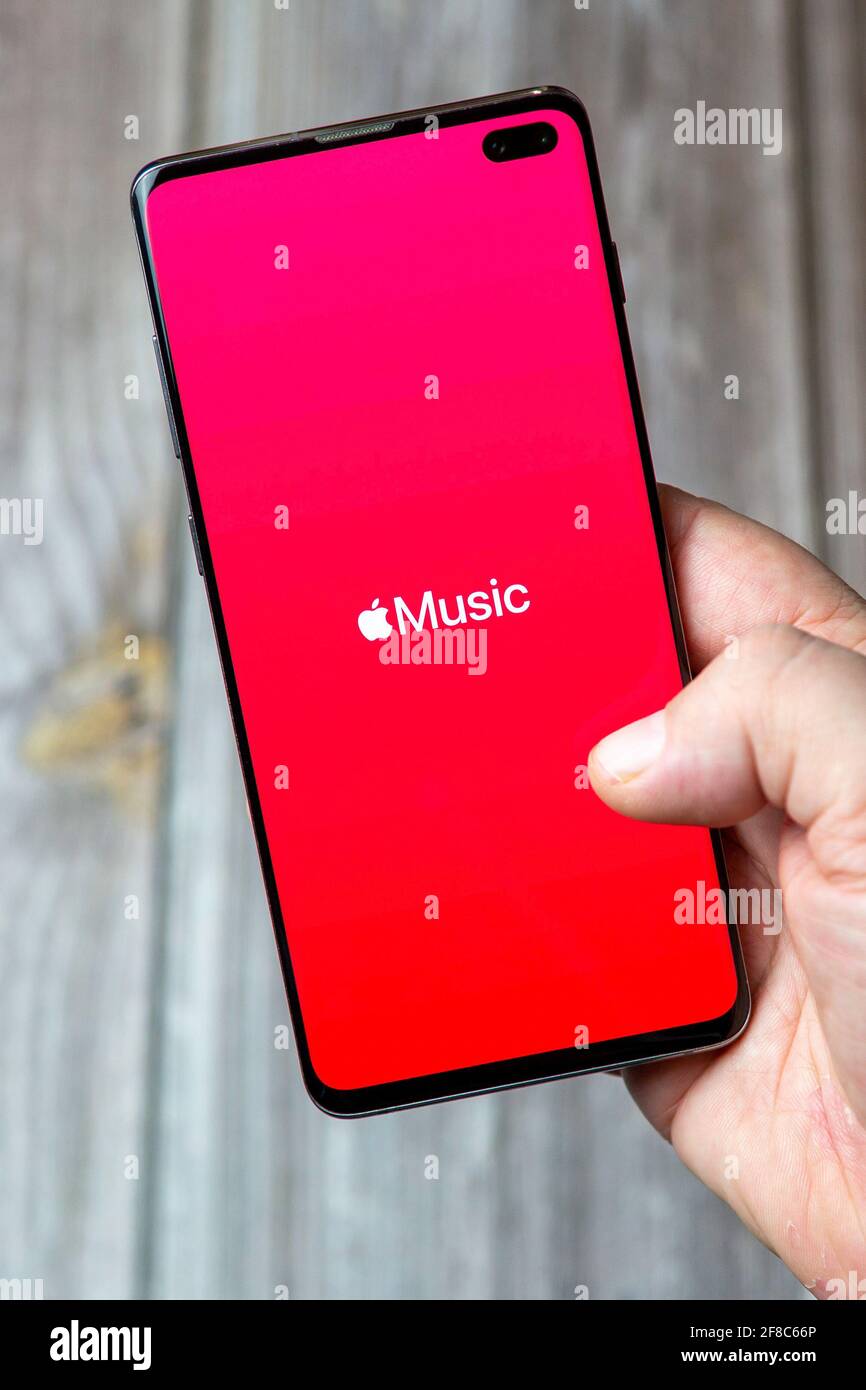 A Mobile phone or cell phone being held in a hand with the Apple Music app open on screen Stock Photo