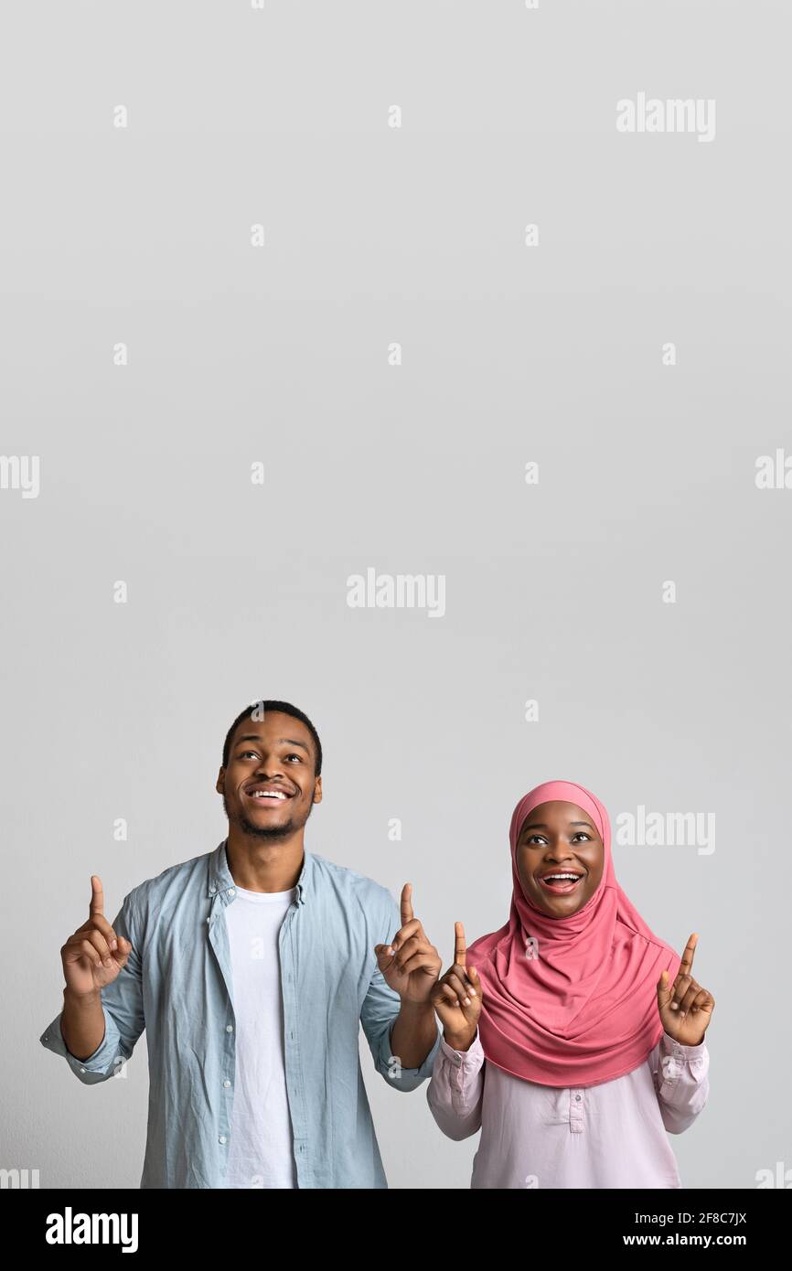 Black man and woman pointing up at empty space Stock Photo