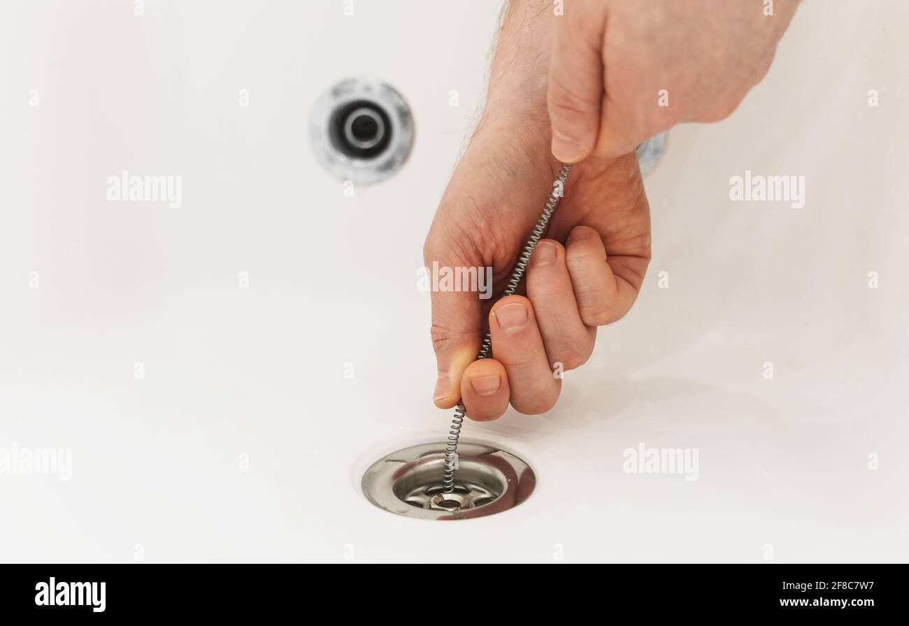 Plumber using drain snake to unclog bathtub Stock Photo - Alamy