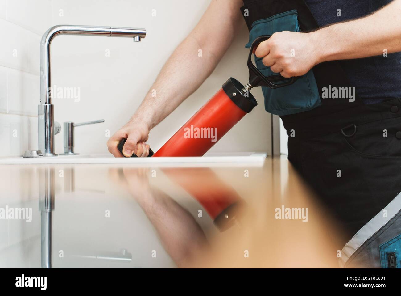 Plumber unclogging kitchen sink with professional force pump cleaner. Stock Photo