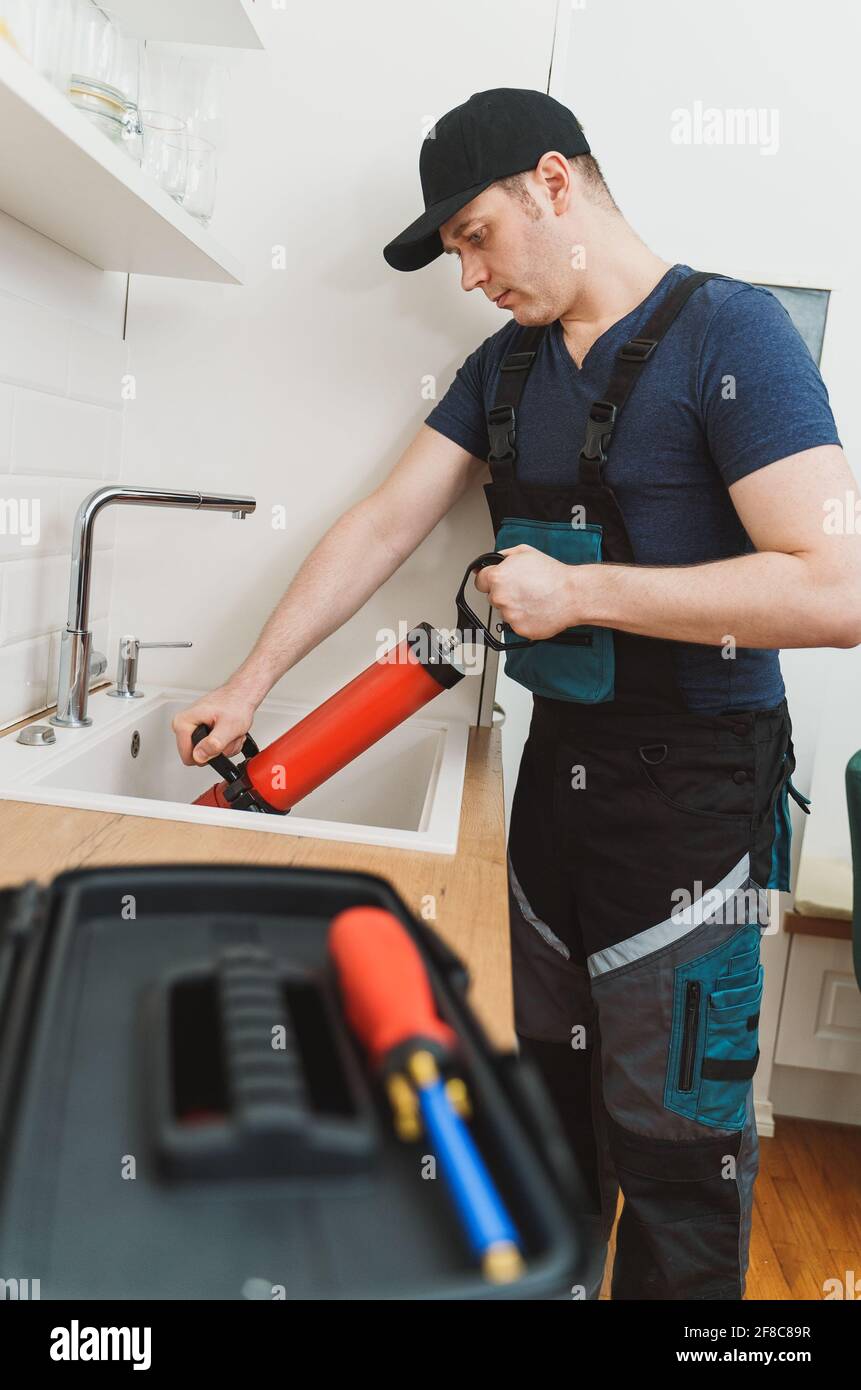 Side View Of A Male Plumber Using Plunger In Kitchen Sink Stock Photo -  Alamy