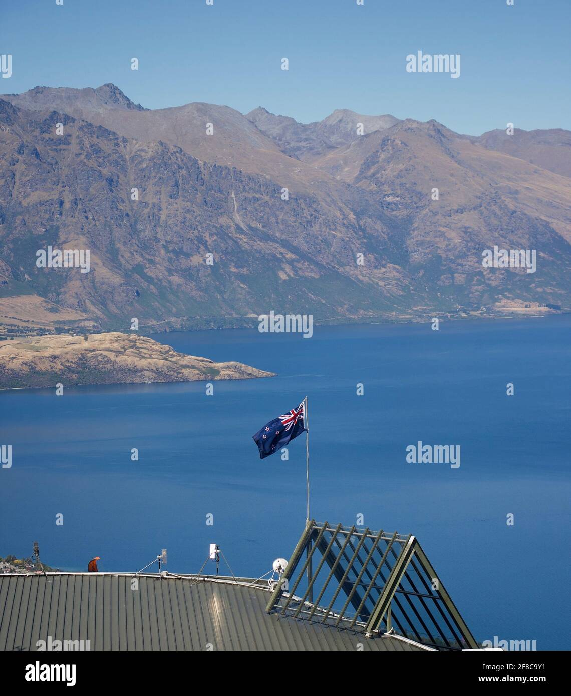 New Zealand flag flies in front of the Remarkables range, Queenstown, New Zealand Stock Photo
