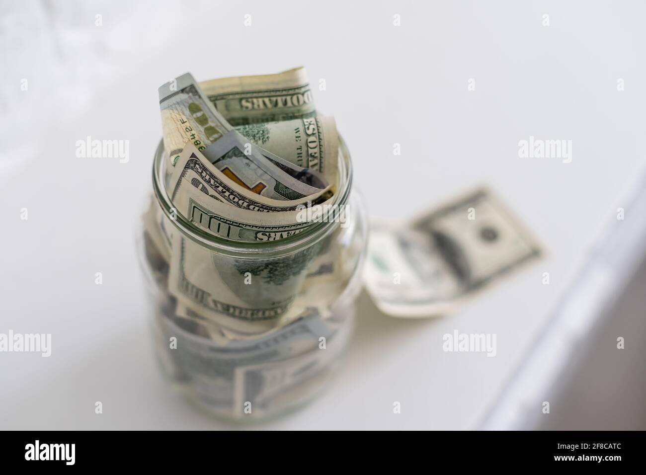 Many dollars bank notes in a glass jar isolated on white background ...