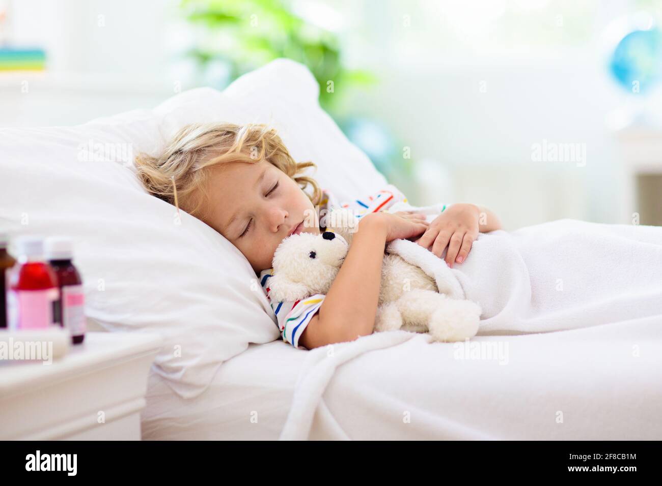 Sick little boy with asthma medicine. Ill child lying in bed. Unwell