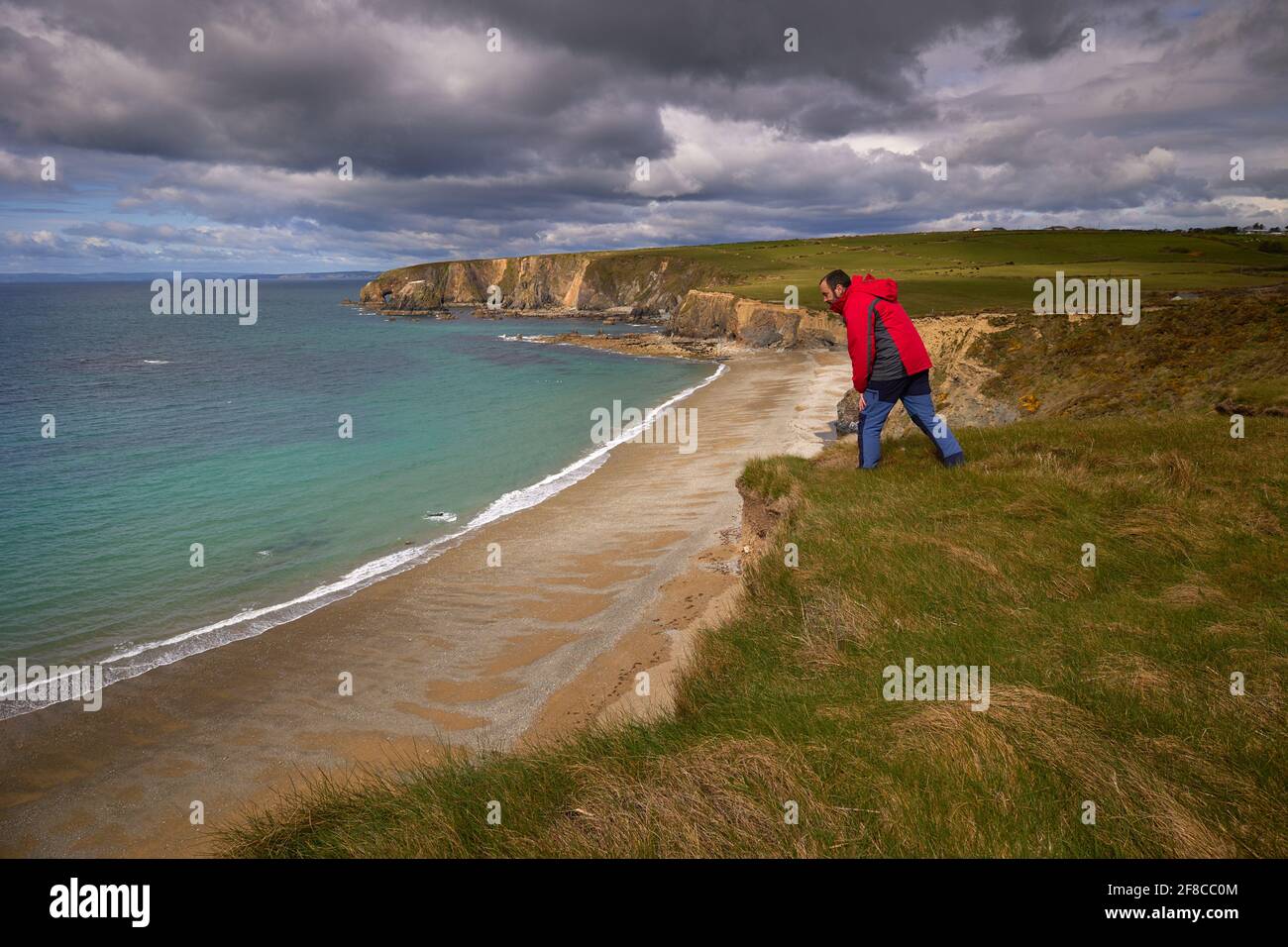 man looking over a cliff of the coast of cooper. Kilfarrasy Beach. Co.Waterford Coastline, Ireland Stock Photo