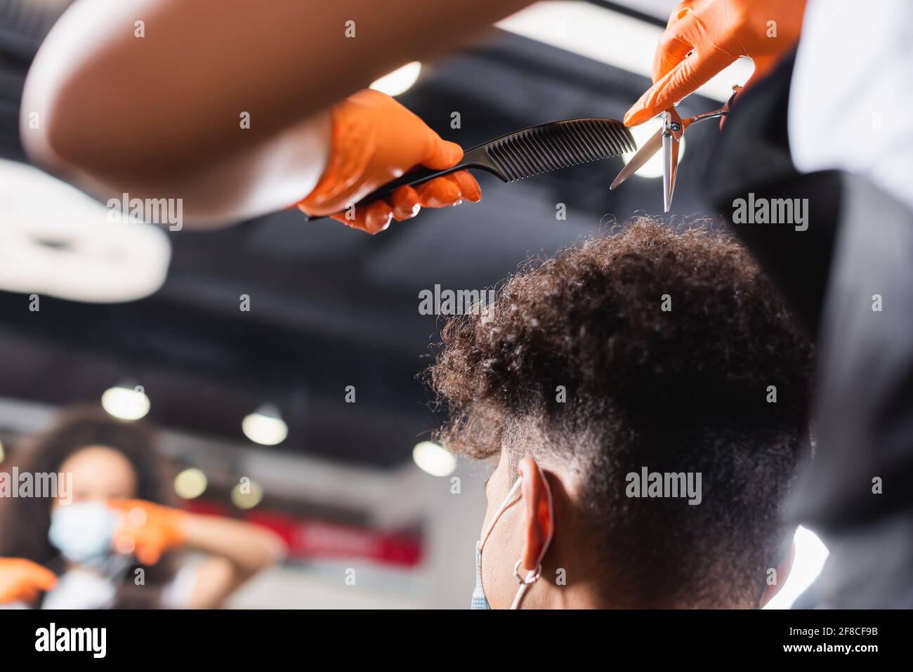 Hairstylist in latex gloves holding comb and scissors near hair of african  american man Stock Photo - Alamy