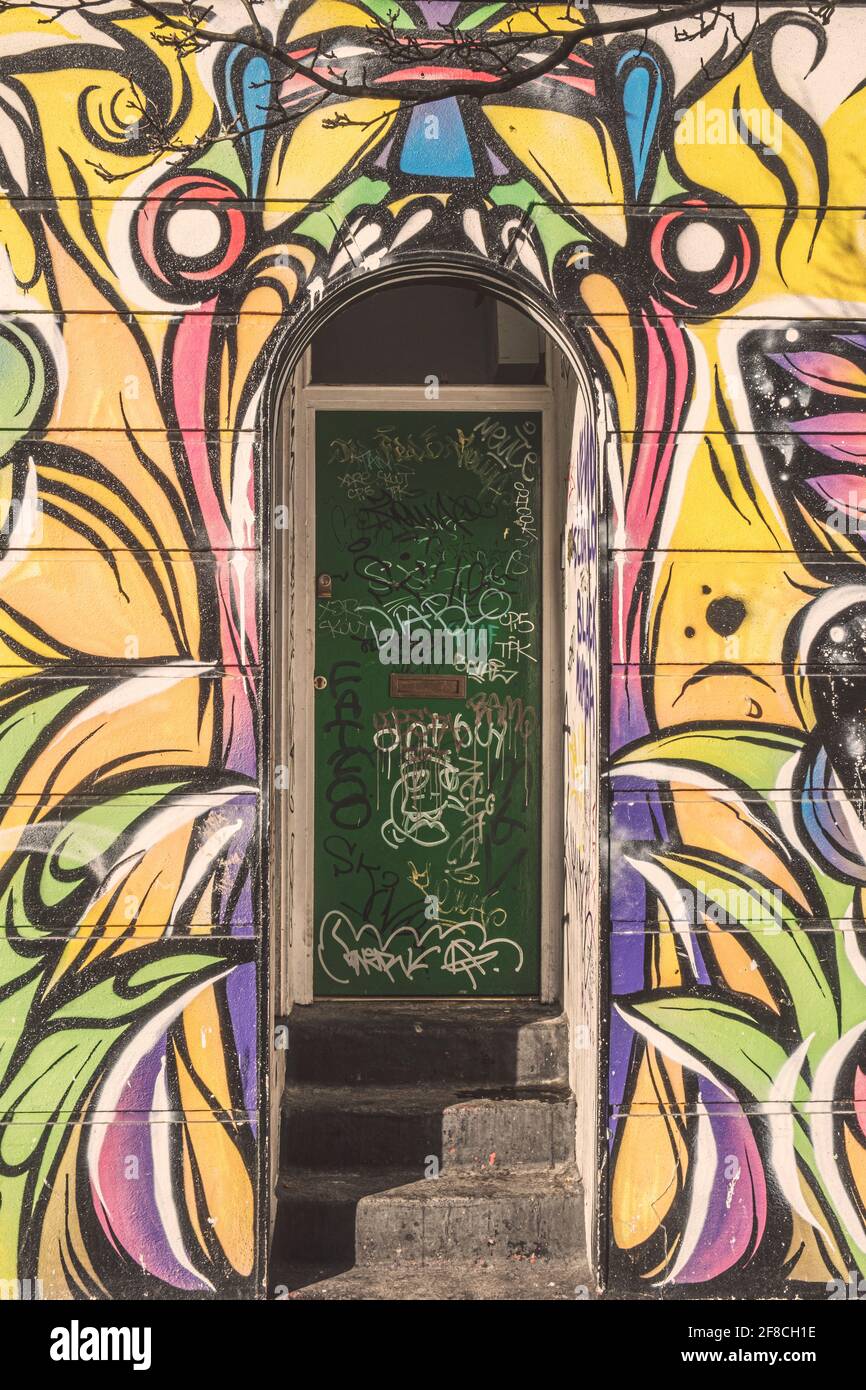Entrance to a squat house in London, covered in graffiti tags and with street art of a gaping mouth, Camden Town, London, United Kingdom Stock Photo