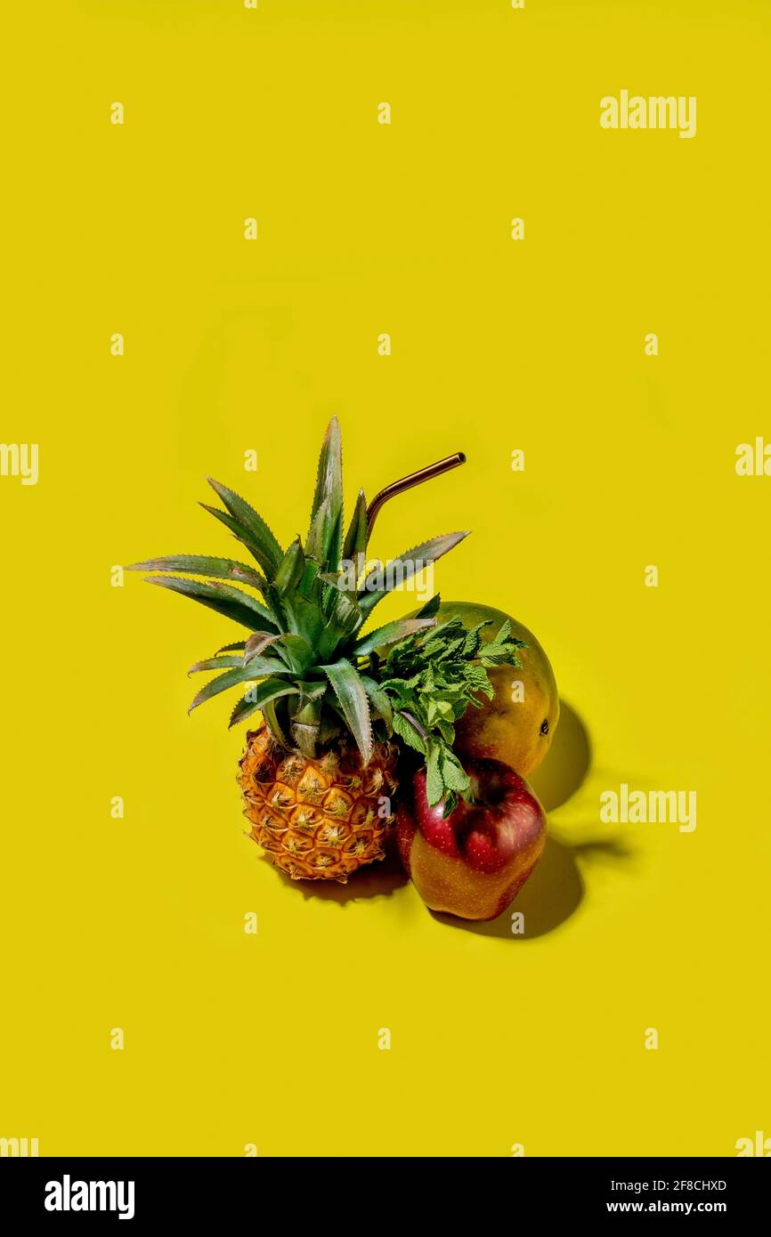 Mini pineapple, mango and apple on a solid yellow background Stock Photo