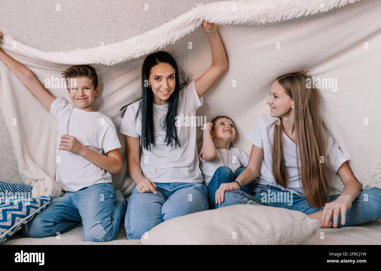 happy mom and her little children are sitting on the couch with a white