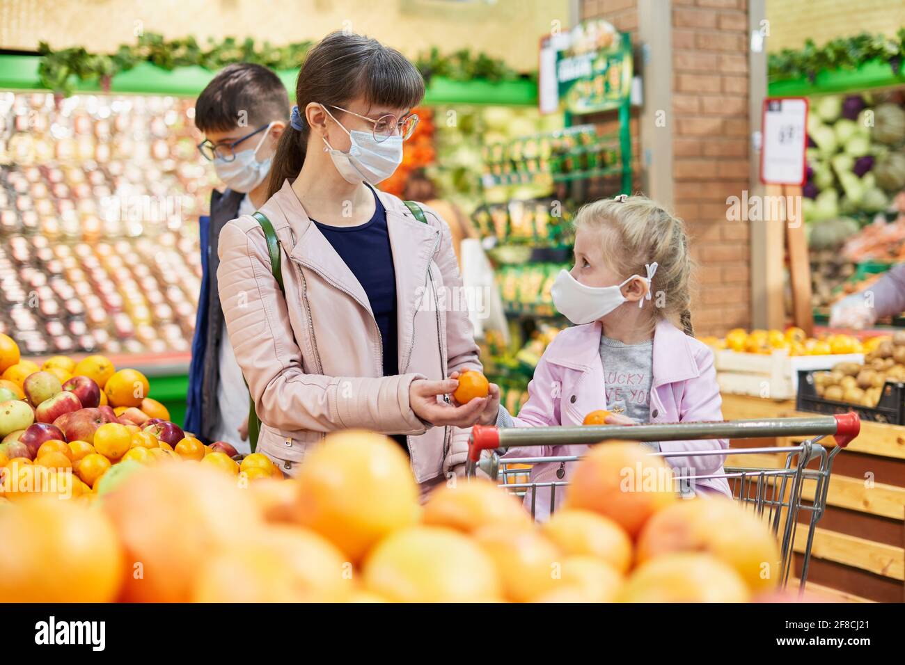 Mom with daughter and son in protective masks at the grocery store