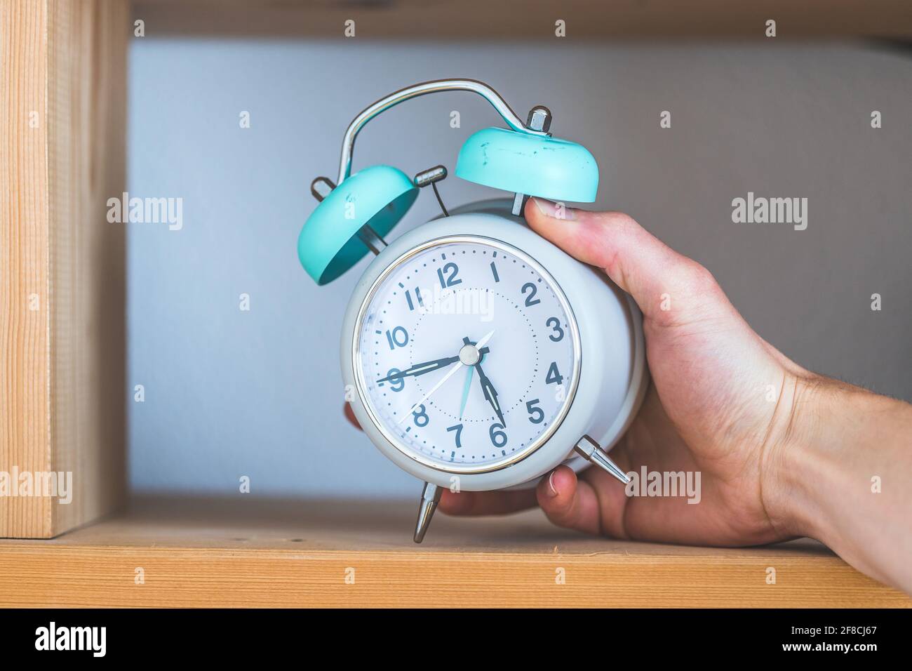 Retro styled white alarm clock in the wooden bookshelf Stock Photo