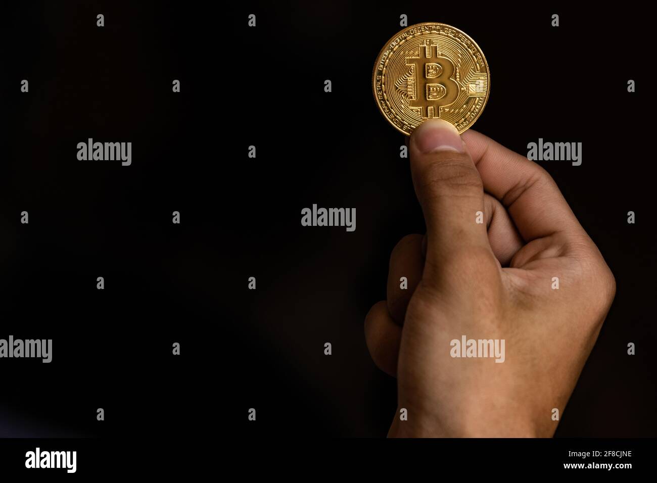 Close up one golden coin with the bitcoin symbol in hand. Young hand holding cryptocurrency coin, Money coins digital, BTC Stock Photo