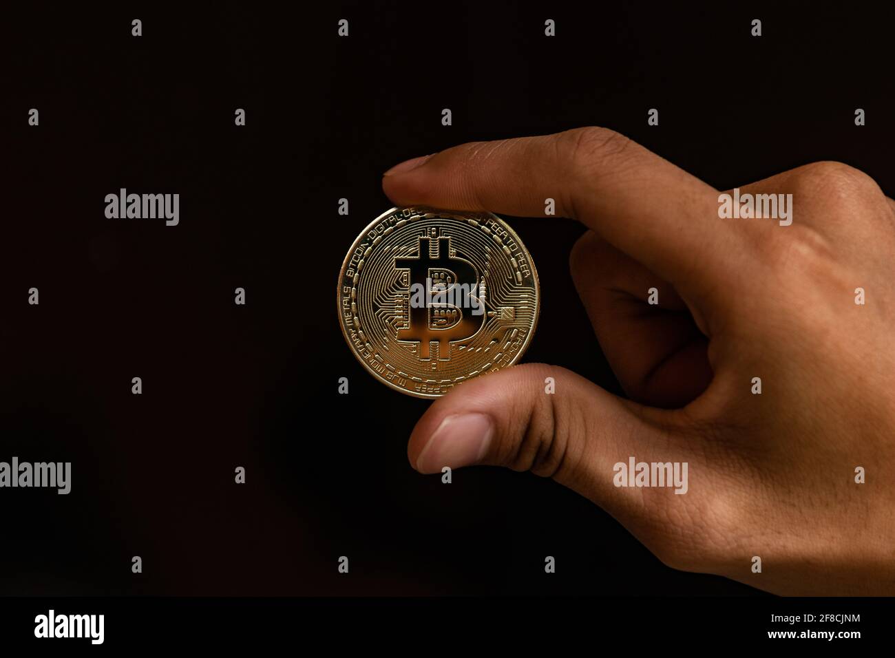 Close up one golden coin with the bitcoin symbol in hand. Young hand holding cryptocurrency coin, Money coins digital, BTC Stock Photo