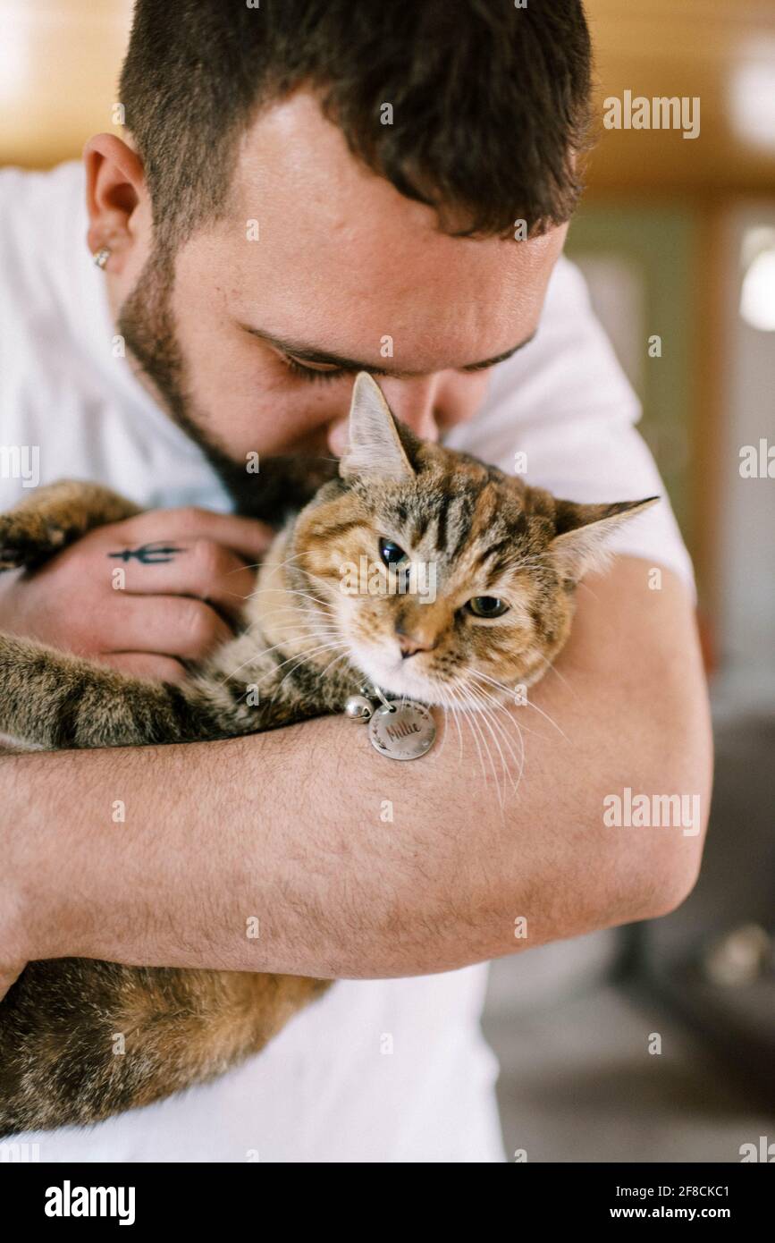 A man holding his cat in his arms and cuddling with her lovingly Stock Photo