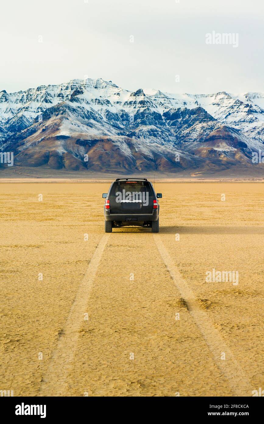 Car Parked On The Desert Playa With Mountain Peaks In The Distance Stock Photo