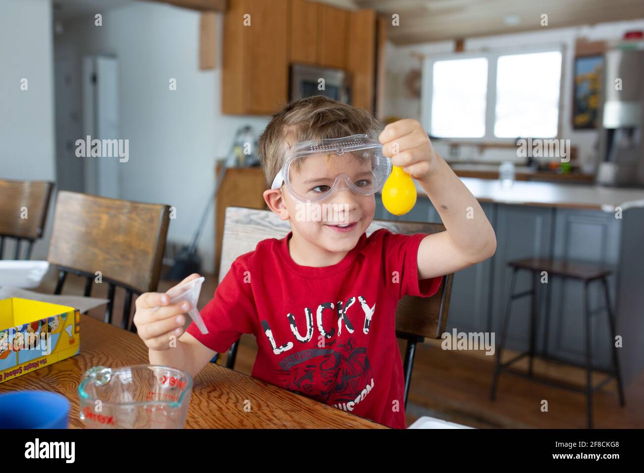 Boy holding up yellow balloon during science experiment at home Stock Photo