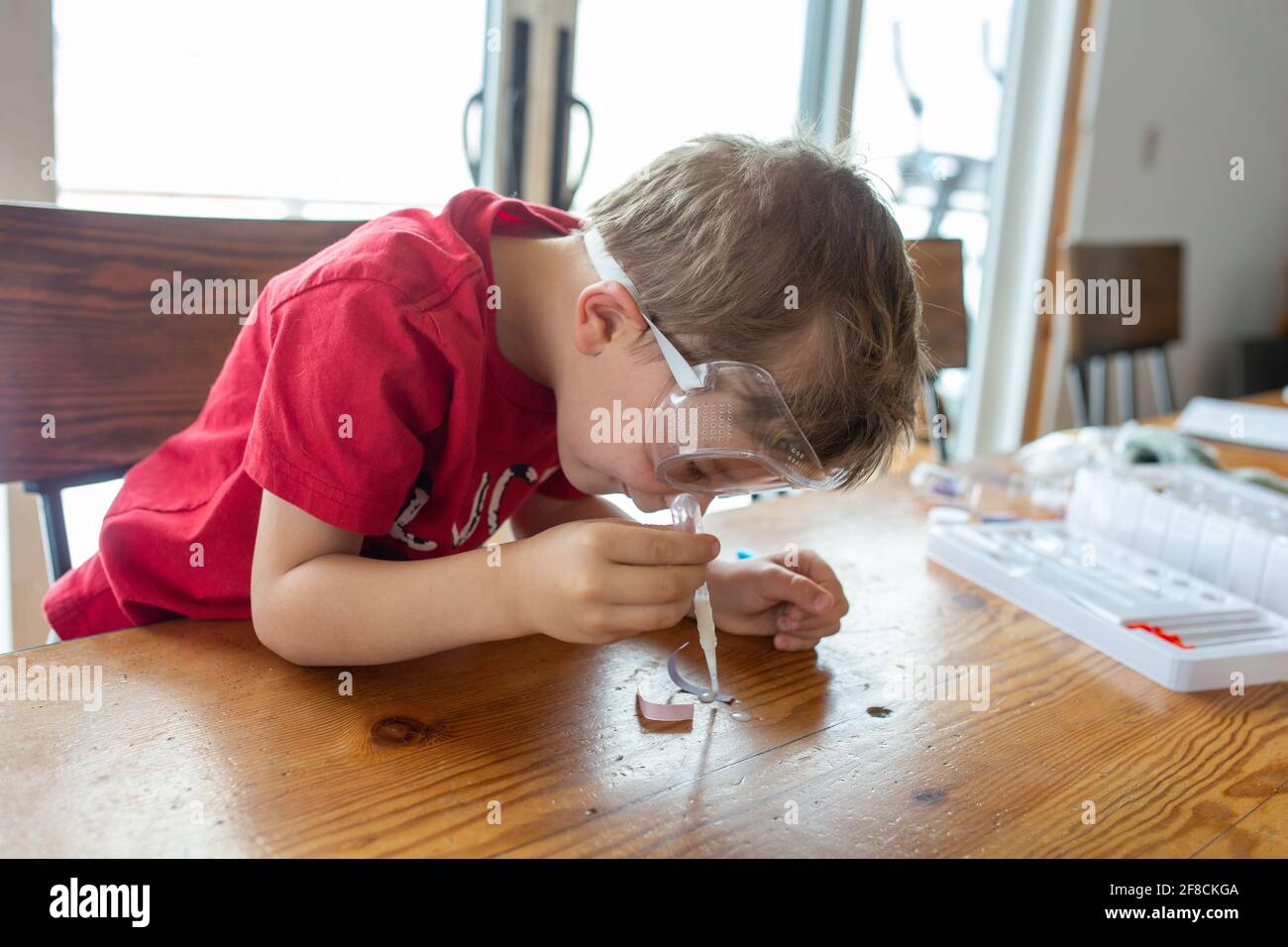 Boy leaning over chemistry set he is playing with Stock Photo