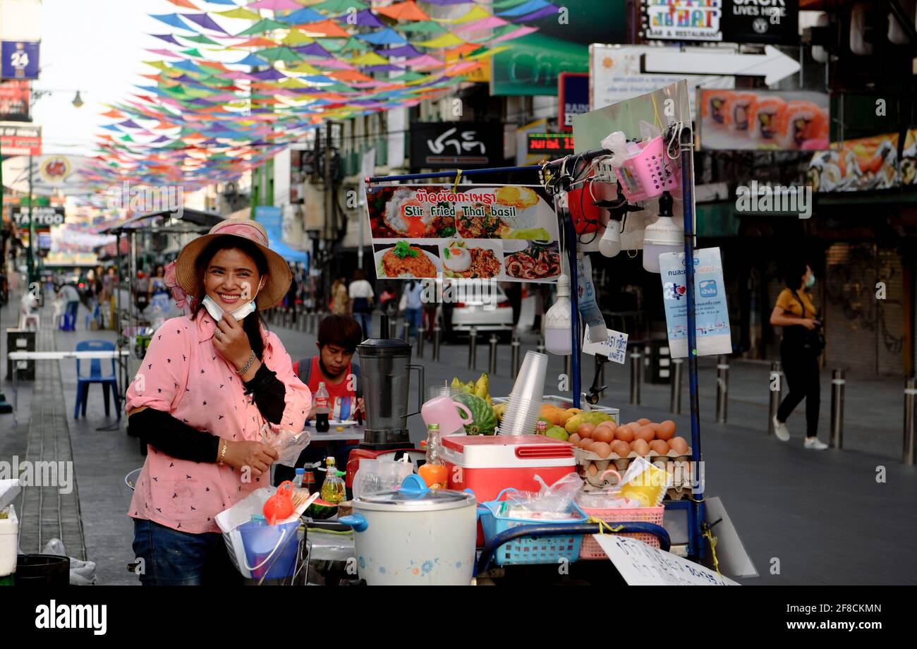 A Thai street food vendor poses for a photo during the Thai New Year Songkran holiday. Normally pre-pandemic covid -19, the street would be full of Thai and foreign tourists enjoying the celebration of the New Year harvest festival with water throwing and revelry. Bar and pubs are closed for 2 weeks during Songkran from April 6-19, 2021. (Photo by Paul Lakatos / SOPA Images/Sipa USA) Stock Photo
