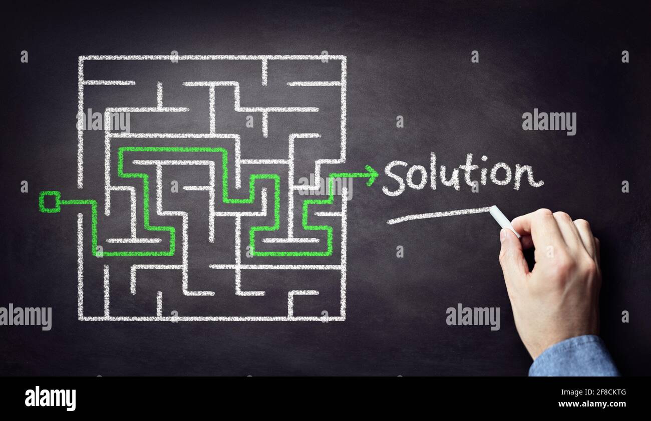 Business strategy businessman planning and finding a solution through a chalk drawing of a maze on blackboard Stock Photo