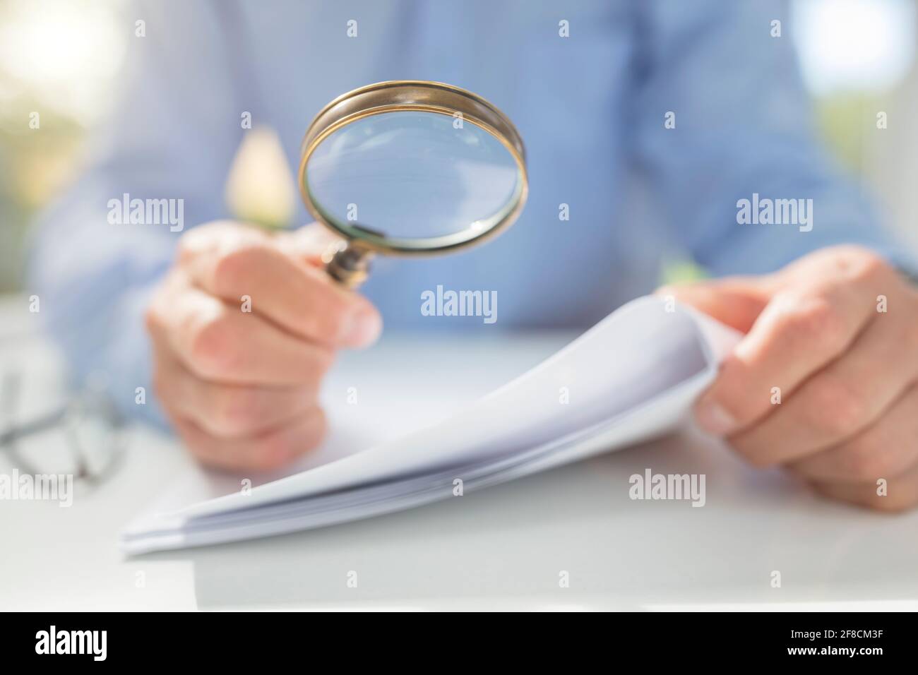 Businessman reading documents with magnifying glass concept for analyzing a finance agreement or legal contract Stock Photo