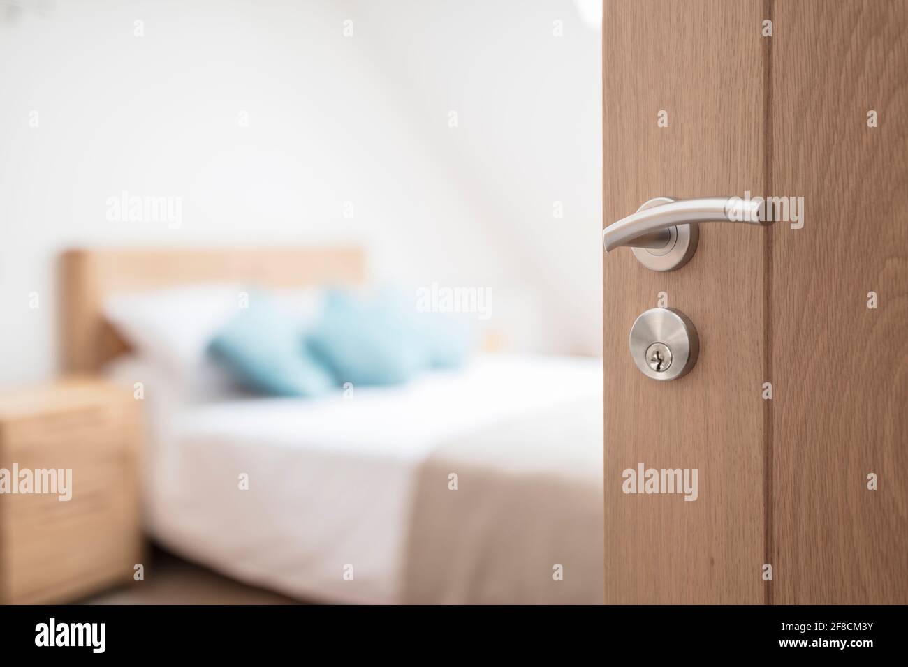 Hotel room or apartment doorway with key and keyring key fob in open door and bedroom in background Stock Photo