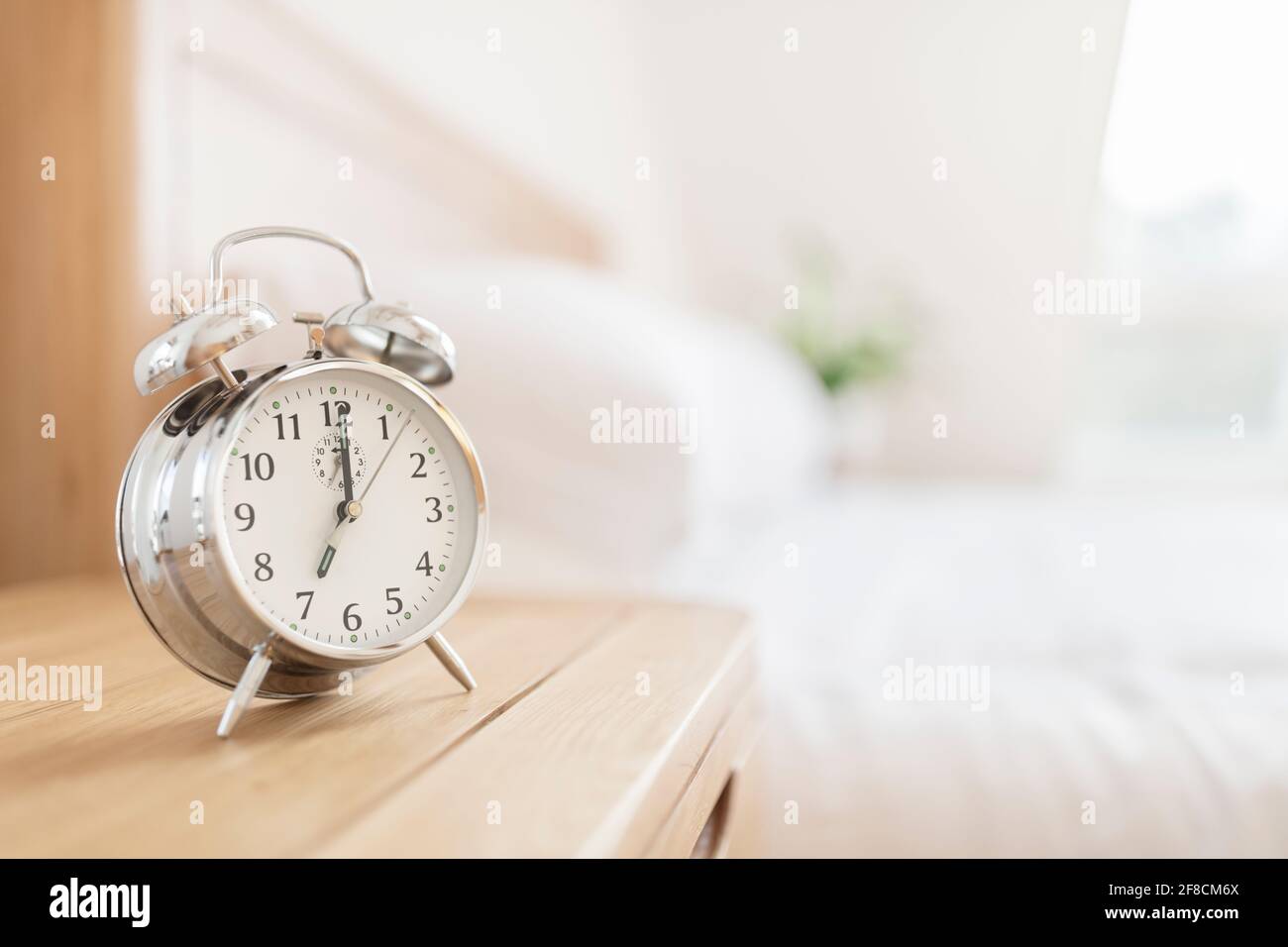 Alarm clock morning wake-up time on bedside table with copy space Stock Photo