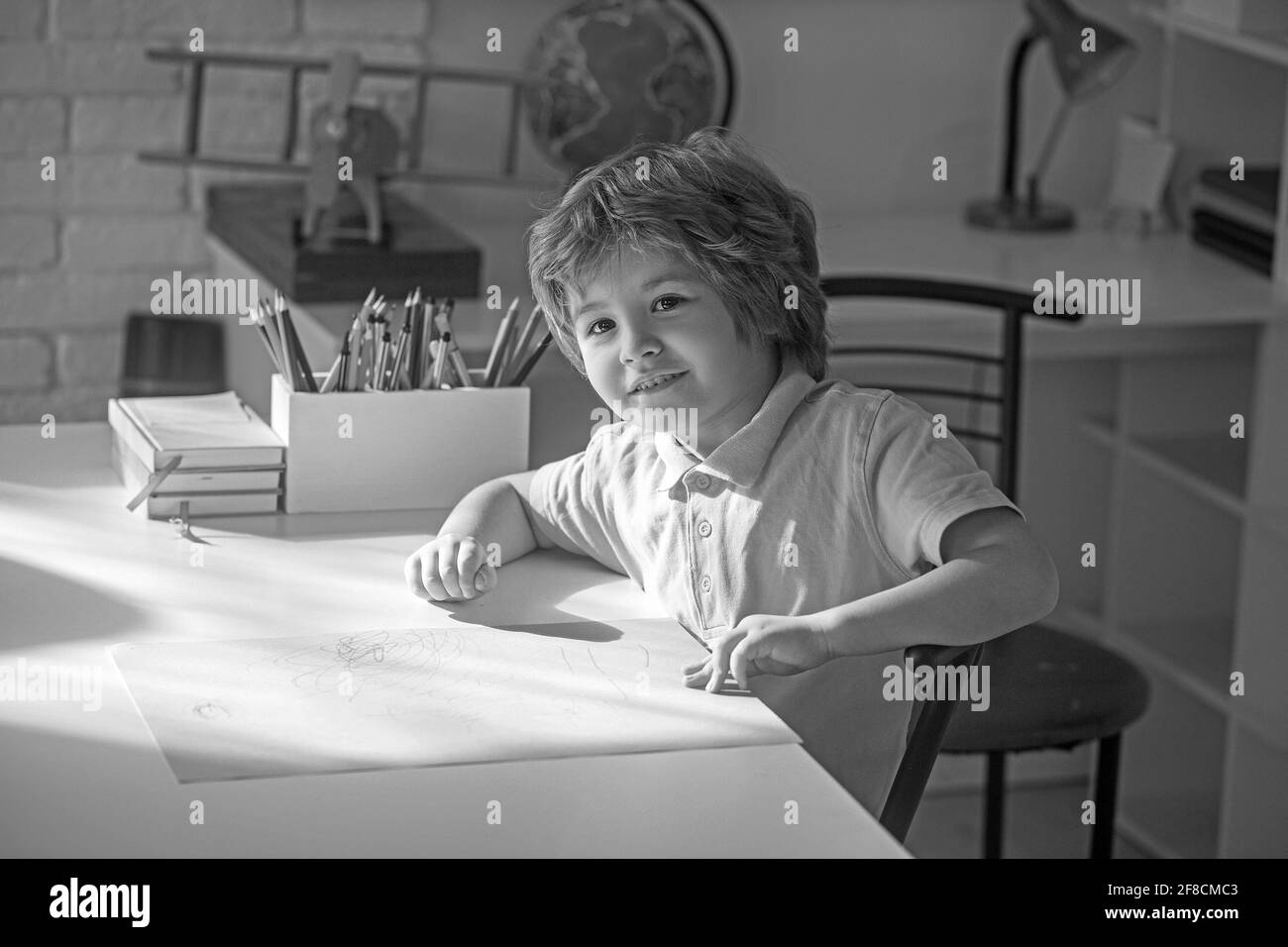 Happy smiling little kid boy at home making homework at the morning before the school starts Stock Photo