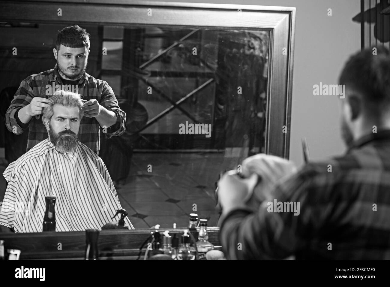 Side view of serious man with stylish modern haircut looking forward in barbershop. Stock Photo
