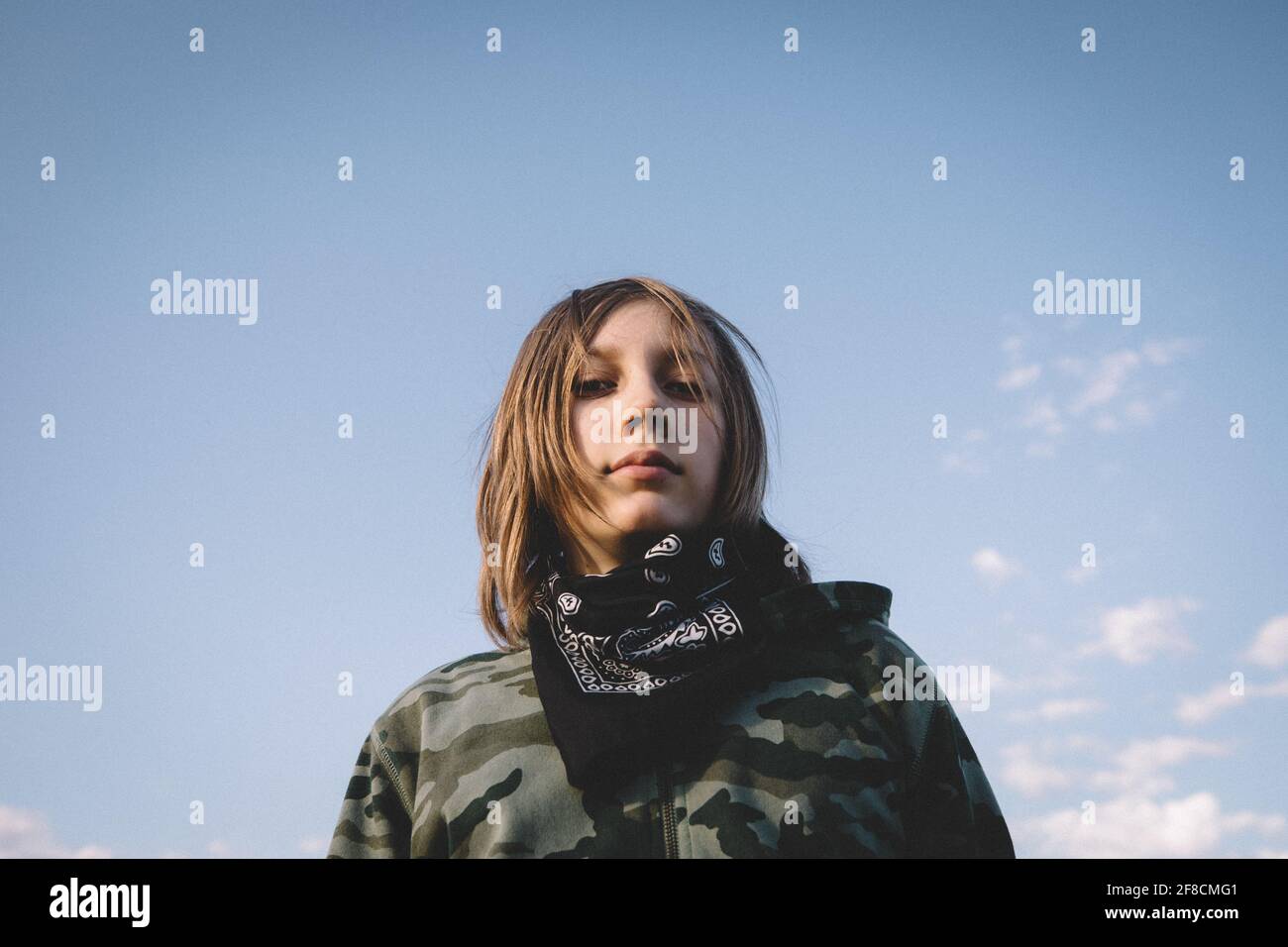 Boy in Camouflage Hoodie and Bandana Against the Open Blue Sky Stock Photo