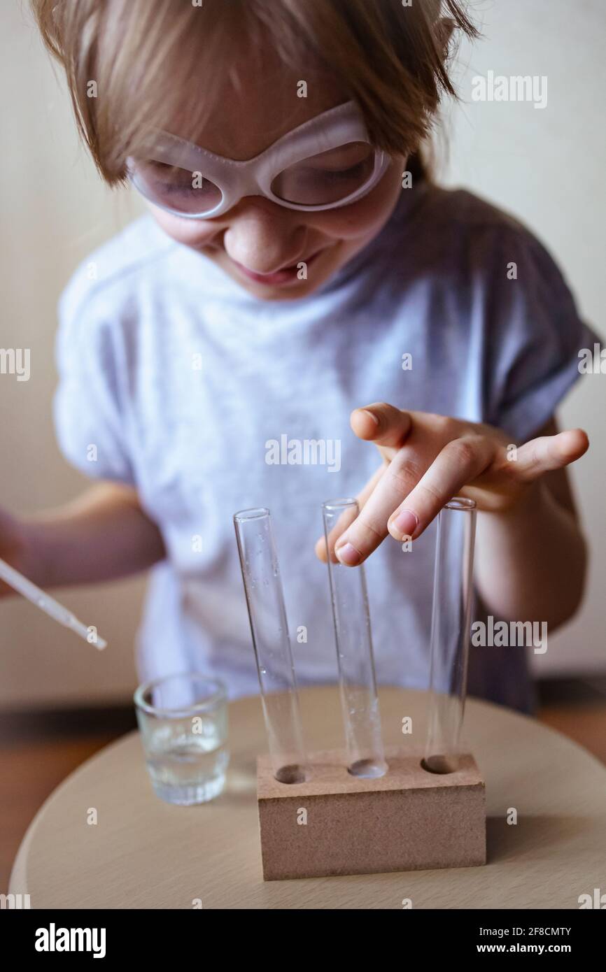 a girl in goggles conducts chemical experiments at home Stock Photo