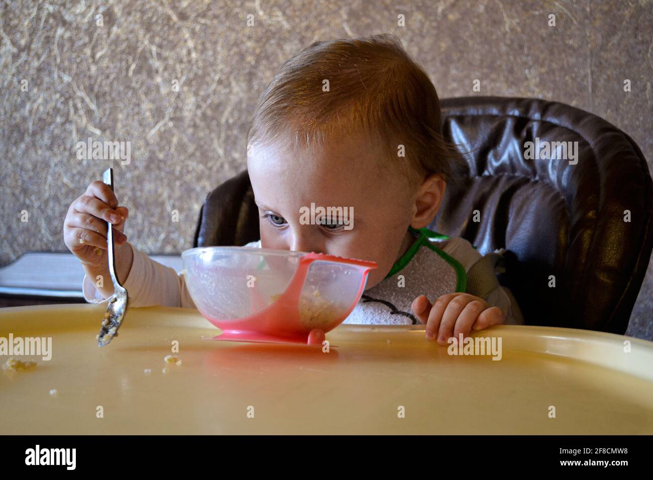baby girl eating porridge from a bowl Stock Photo