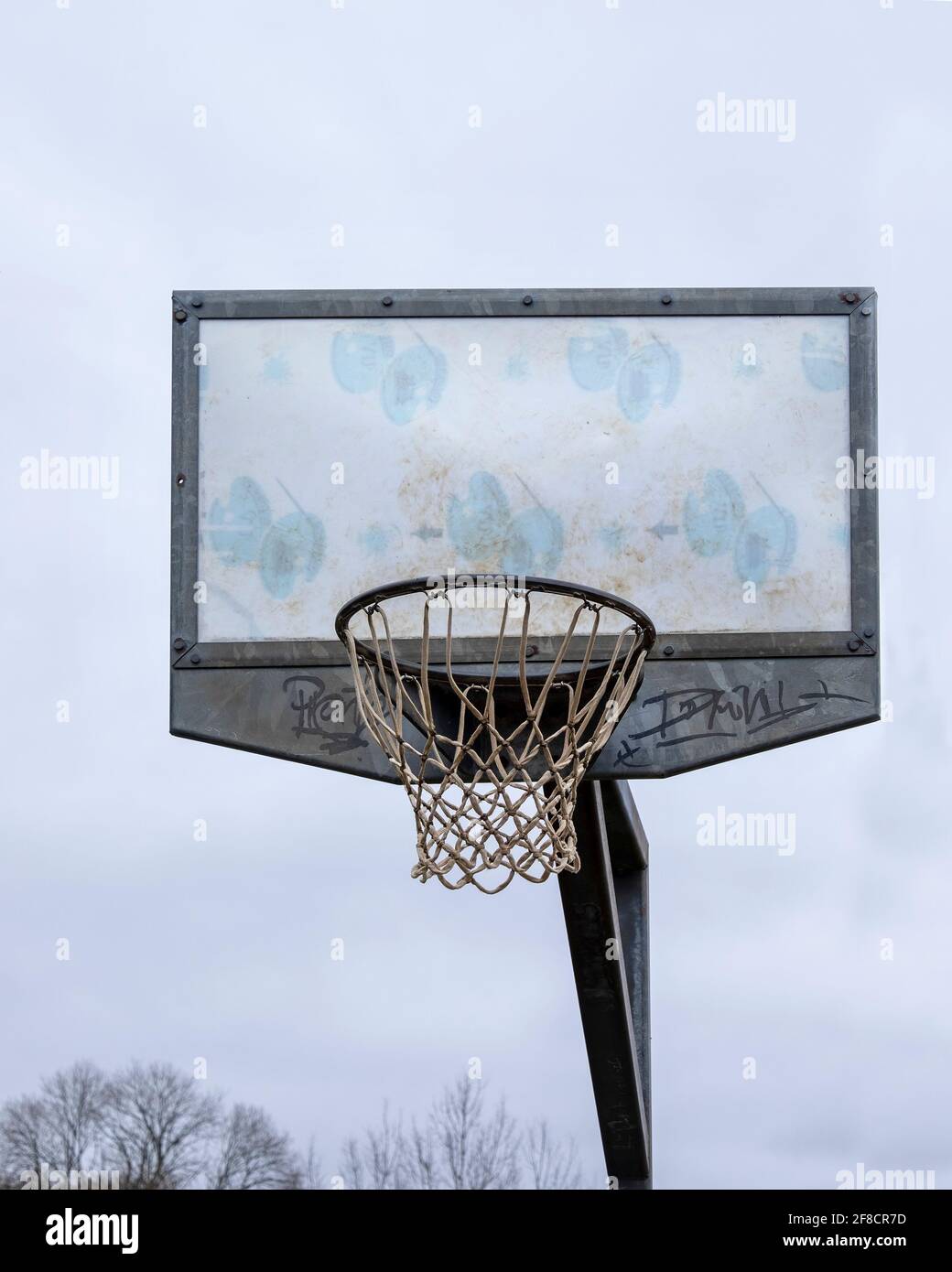 Basketball net on high pole against a grey sky. Stock Photo