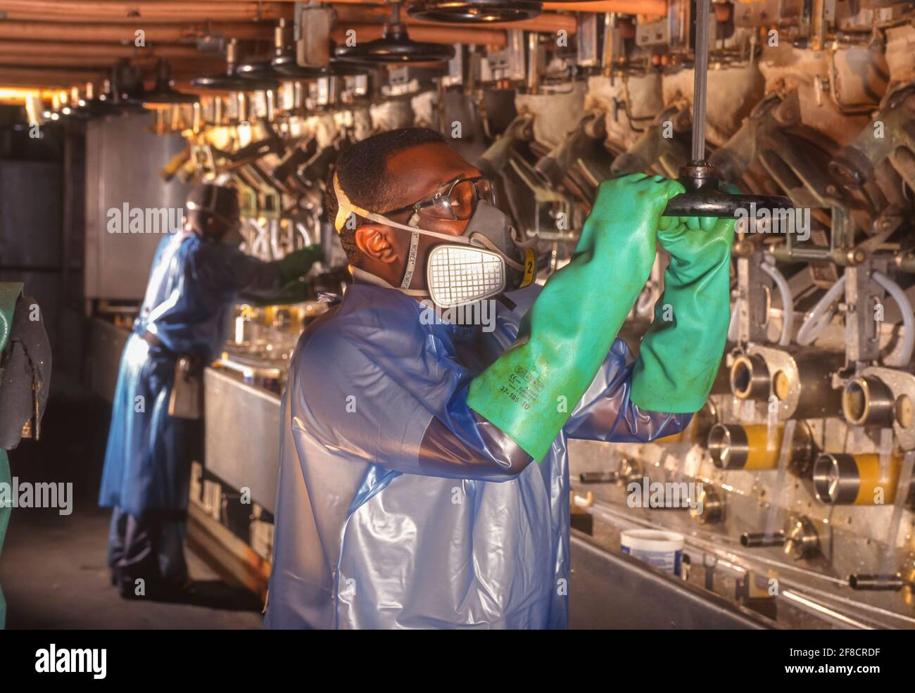 RICHMOND, VIRGINIA, USA, APRIL 16, 1998 - Worker wearing protective gear adjusts valve on Nomex machine in DuPont plant. Stock Photo