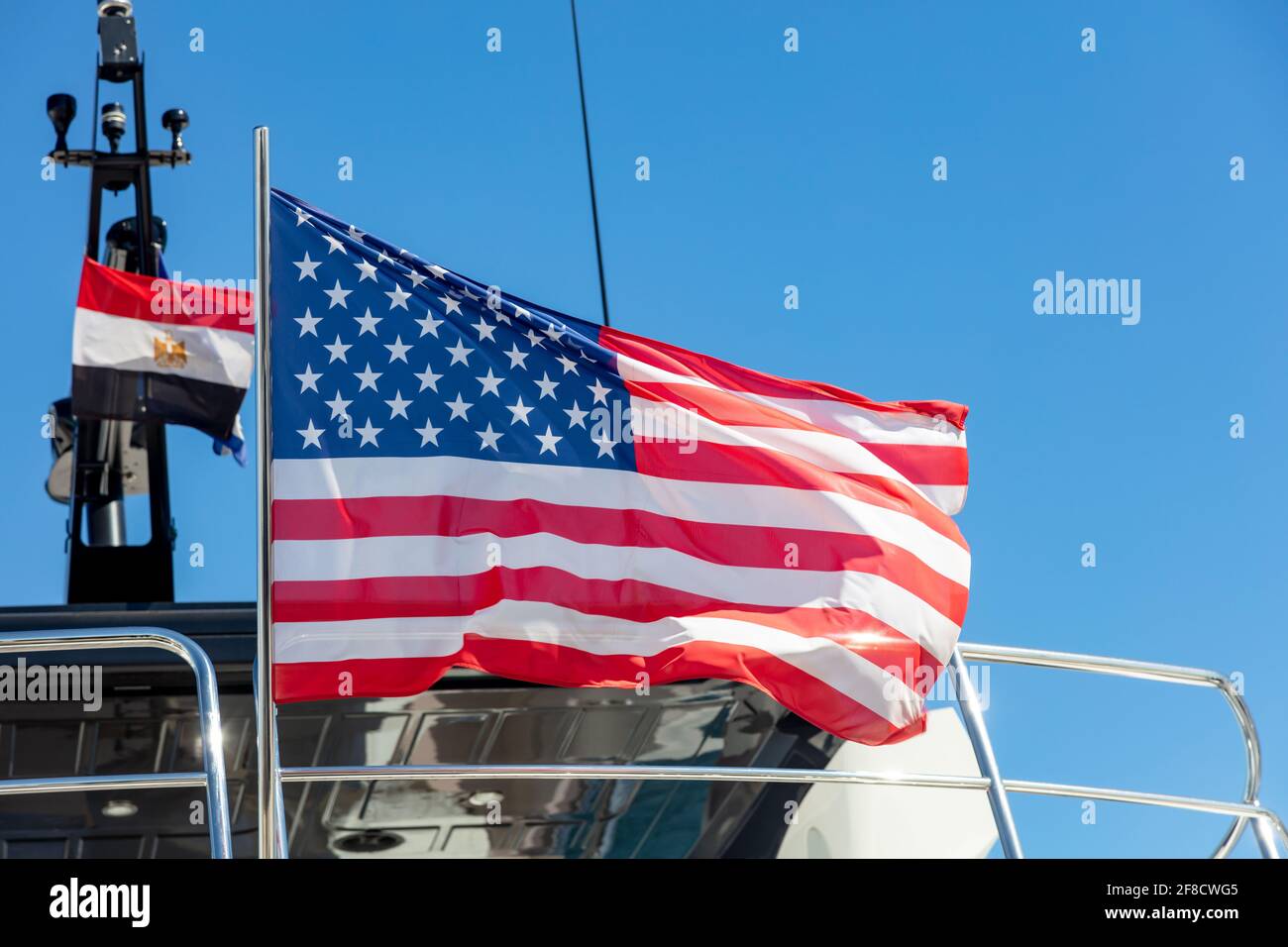United states of America flag waving on yacht stern. Luxury boat moored at marina in Athens Greece. Blue sky background, close up view. Stock Photo