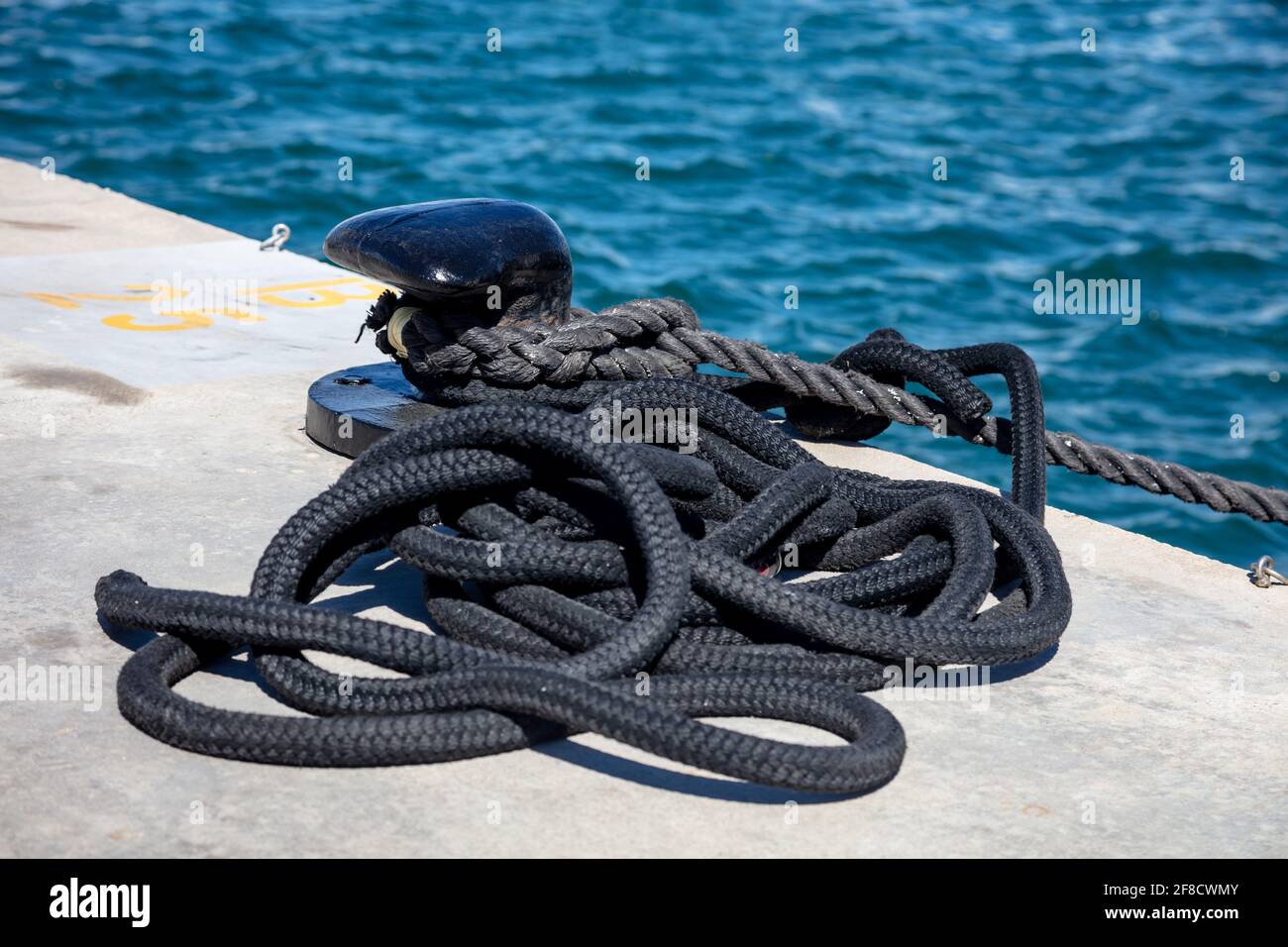 Mooring rope and bollard on sea water and yachts background. Boat heavy