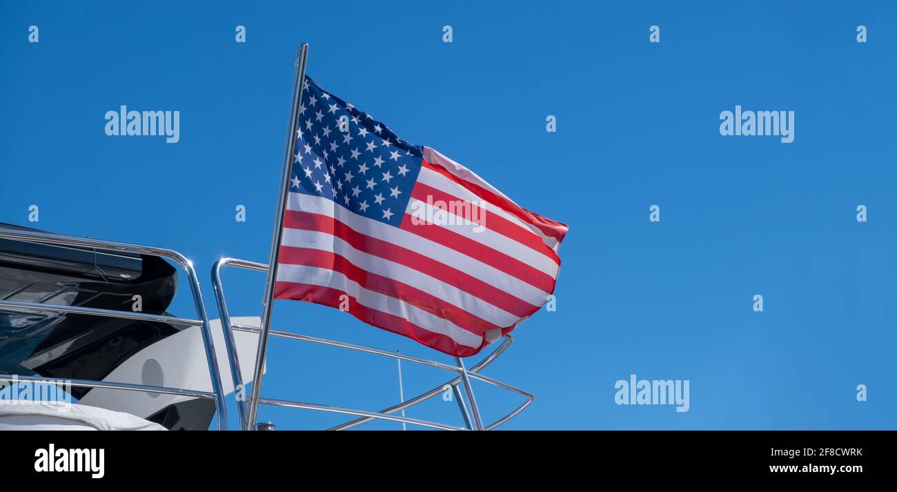 United states of America flag waving on yacht stern. Luxury boat moored at marina in Athens Greece. Blue sky background, copy space. Stock Photo