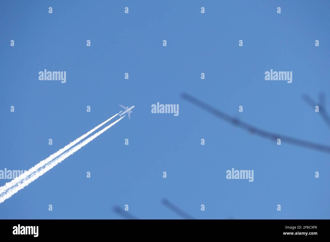 A jet plane in the sky. a double track from a jet plane in a blue sky. Stock Photo