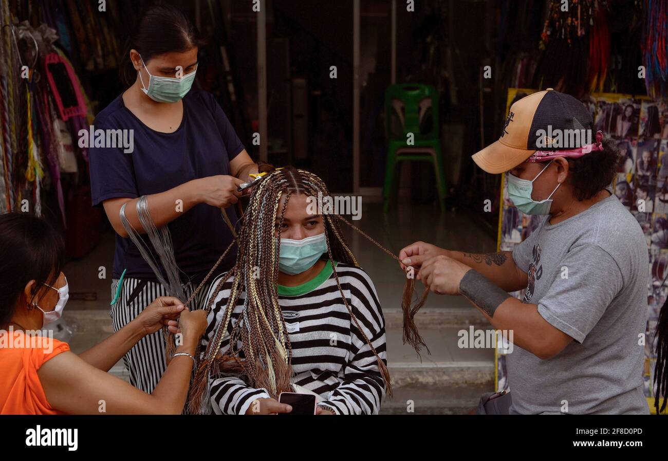 Bangkok, Thailand. 13th Apr, 2021. Thai women seen braiding hair during the Thai New Year Songkran holiday. Normally pre-pandemic covid -19, the street would be full of Thai and foreign tourists enjoying the celebration of the New Year harvest festival with water throwing and revelry. Bar and pubs are closed for 2 weeks during Songkran from April 6-19, 2021. Credit: SOPA Images Limited/Alamy Live News Stock Photo