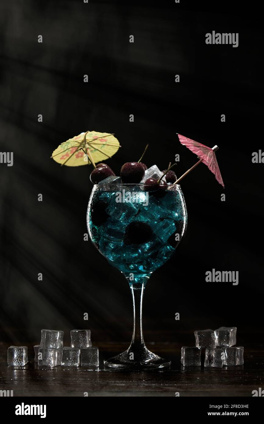 Blue cocktail in a glass with ice and cherry Stock Photo