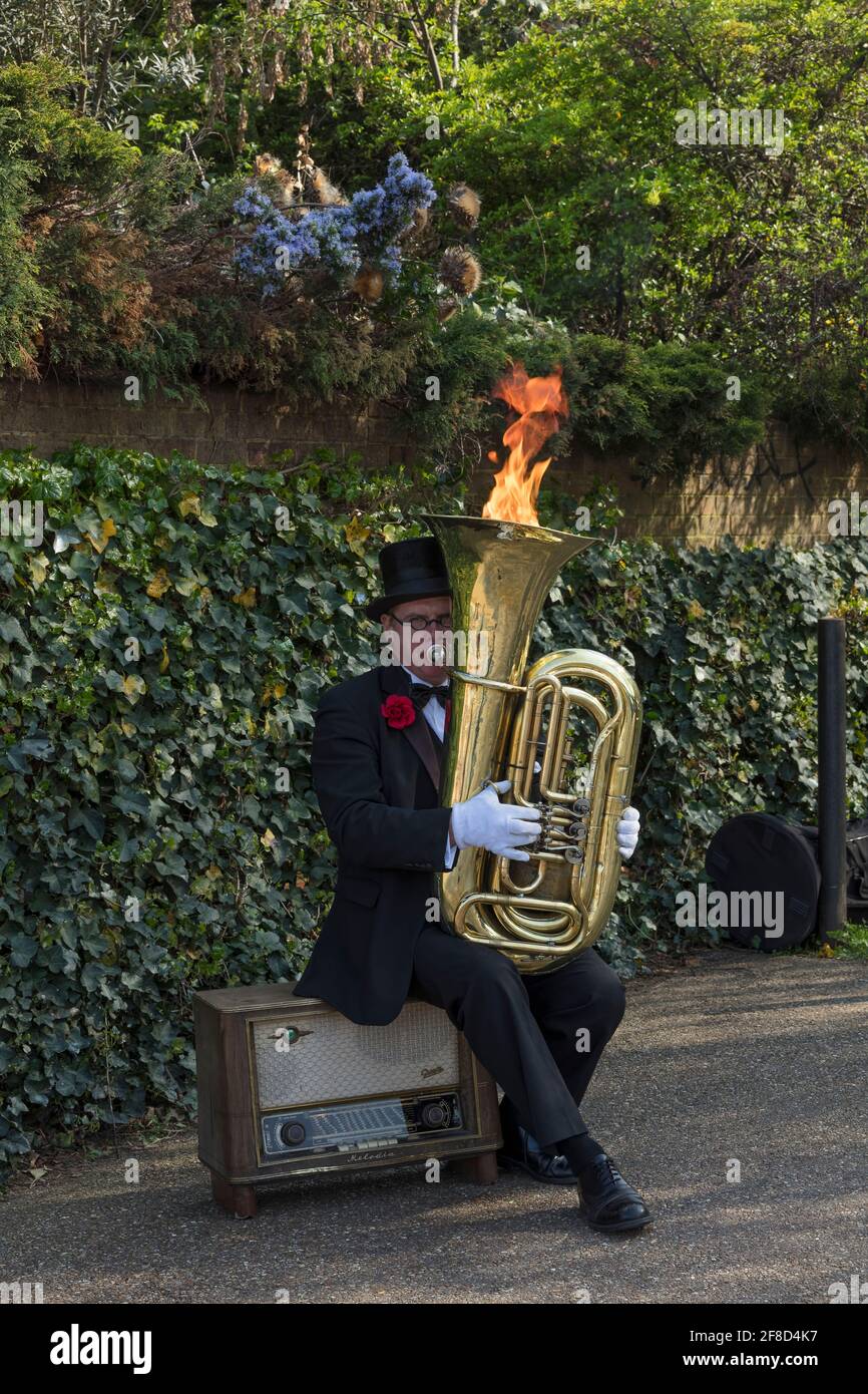 Busker on Bankside London with a brass musical instrument with flames ...