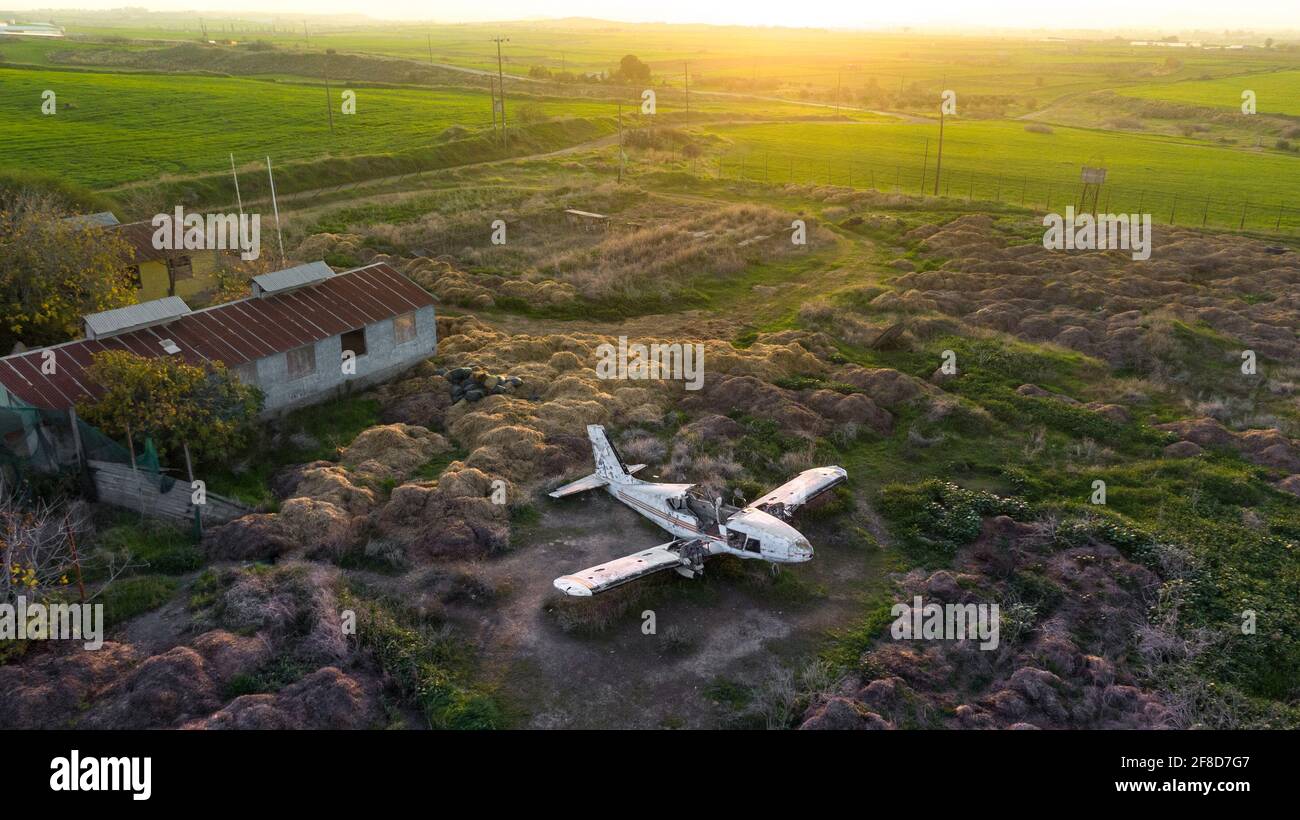 Abandoned broken plane in a field in countryside during sunset, aerial view Stock Photo
