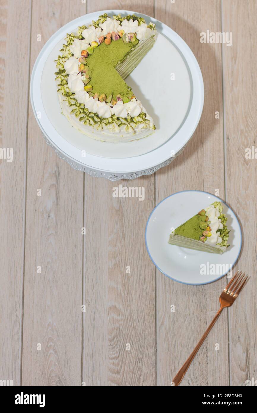 Matcha Mille Crepe Cake Presented On A Cake Holder With A Slice On A Plate. Stock Photo