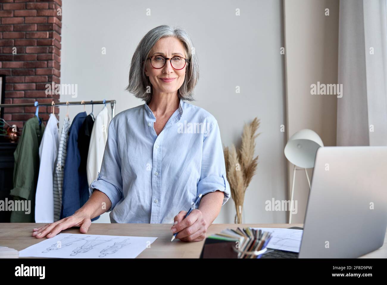 Portrait of mature fashion designer in showroom looking smiling in camera. Stock Photo