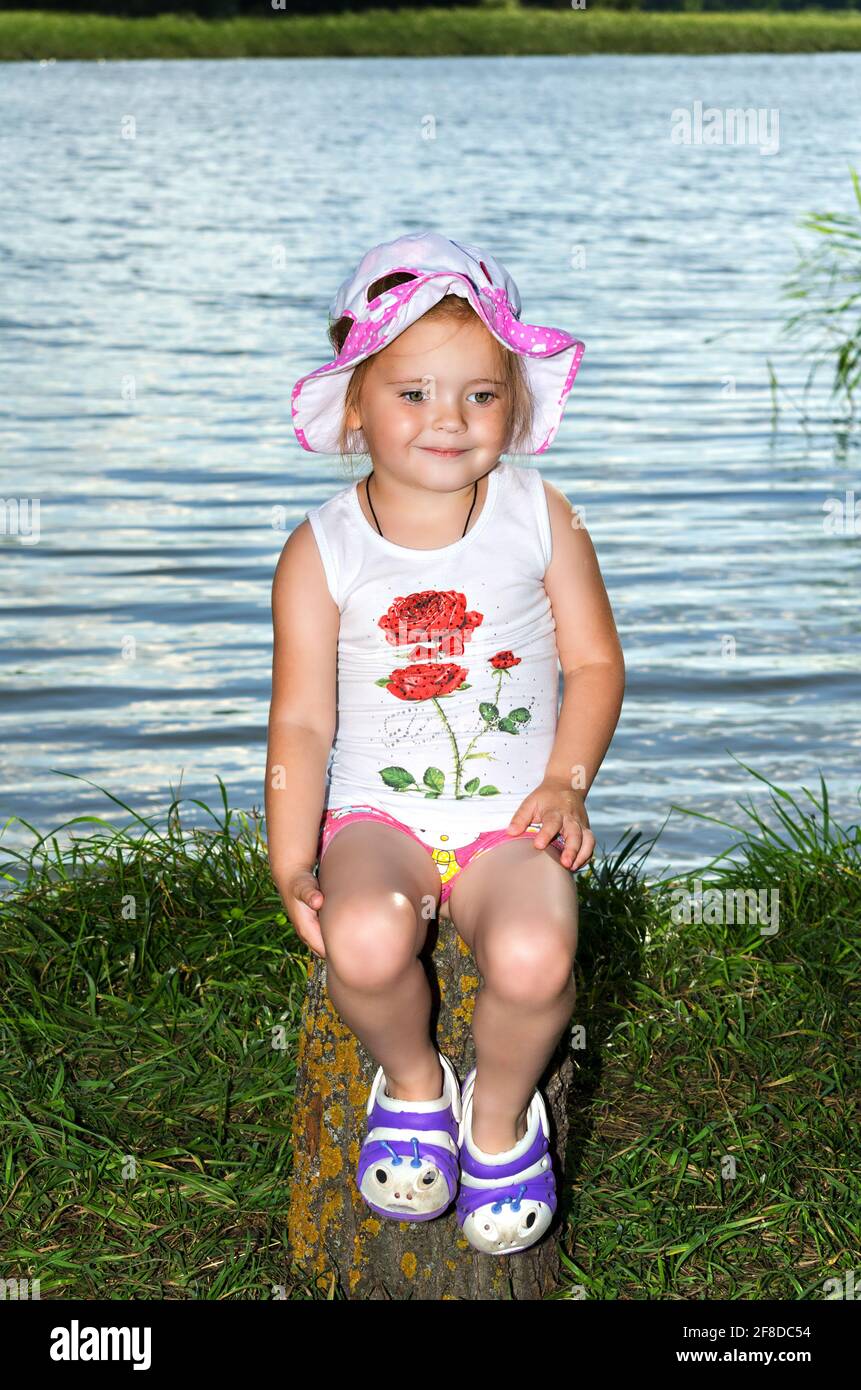 Little girl sits on the bank of a river. Selective focus Stock Photo ...