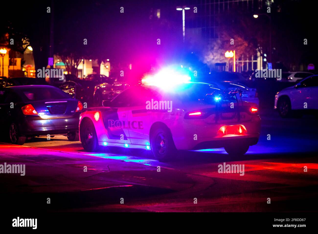 Police car with emergency lights flashing at night in city from the back Stock Photo